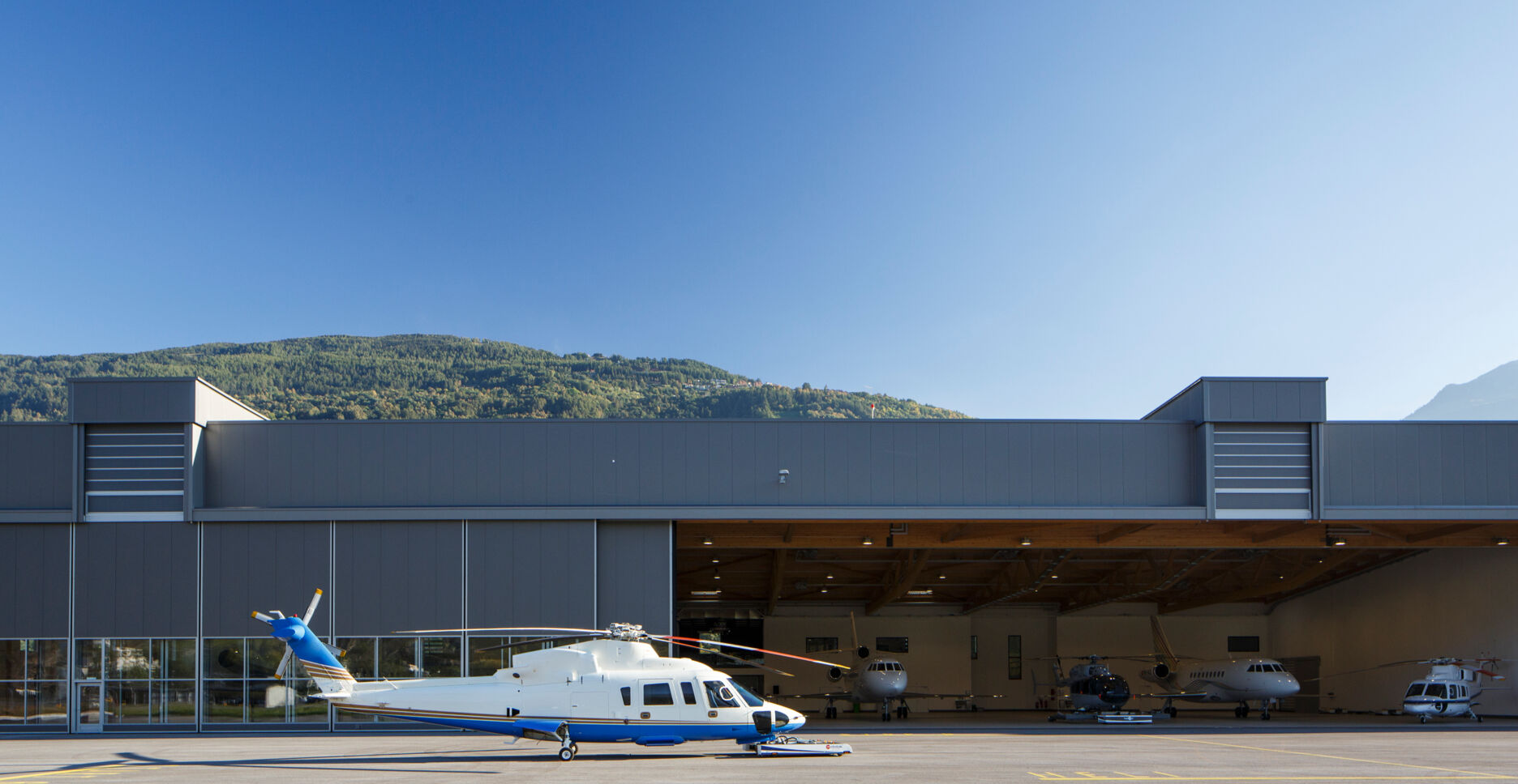Weiss-blauer Helikopter draussen vor der Flugzeughalle