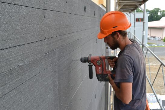 Un operaio edile fa un buco nell'isolamento Centre de renfort de la Veveyse