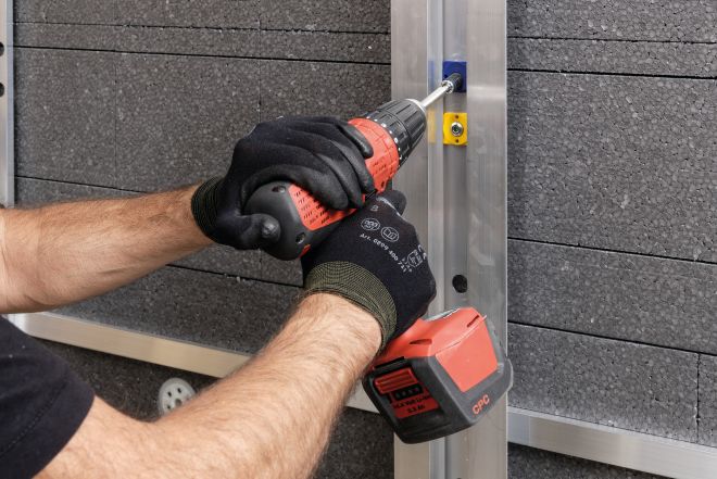 Ein Bauarbeiter verschraubt eine Distanzschraube auf einem Aluwinkel VENTO Distanzschraube